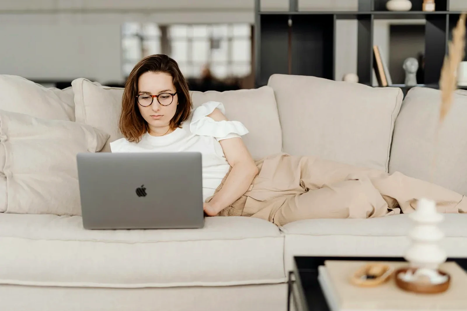 Freelancer working from a calm sofa setup with a laptop in a warm, minimal interior.