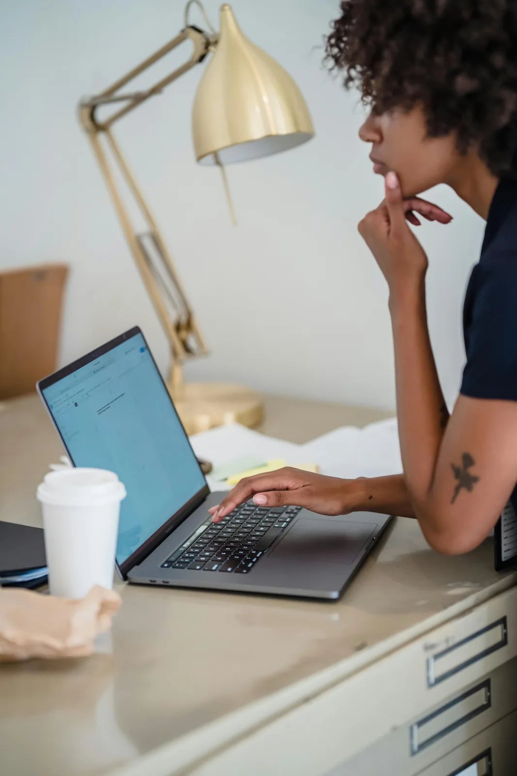 Freelancer focused on a laptop while reviewing work at a desk.
