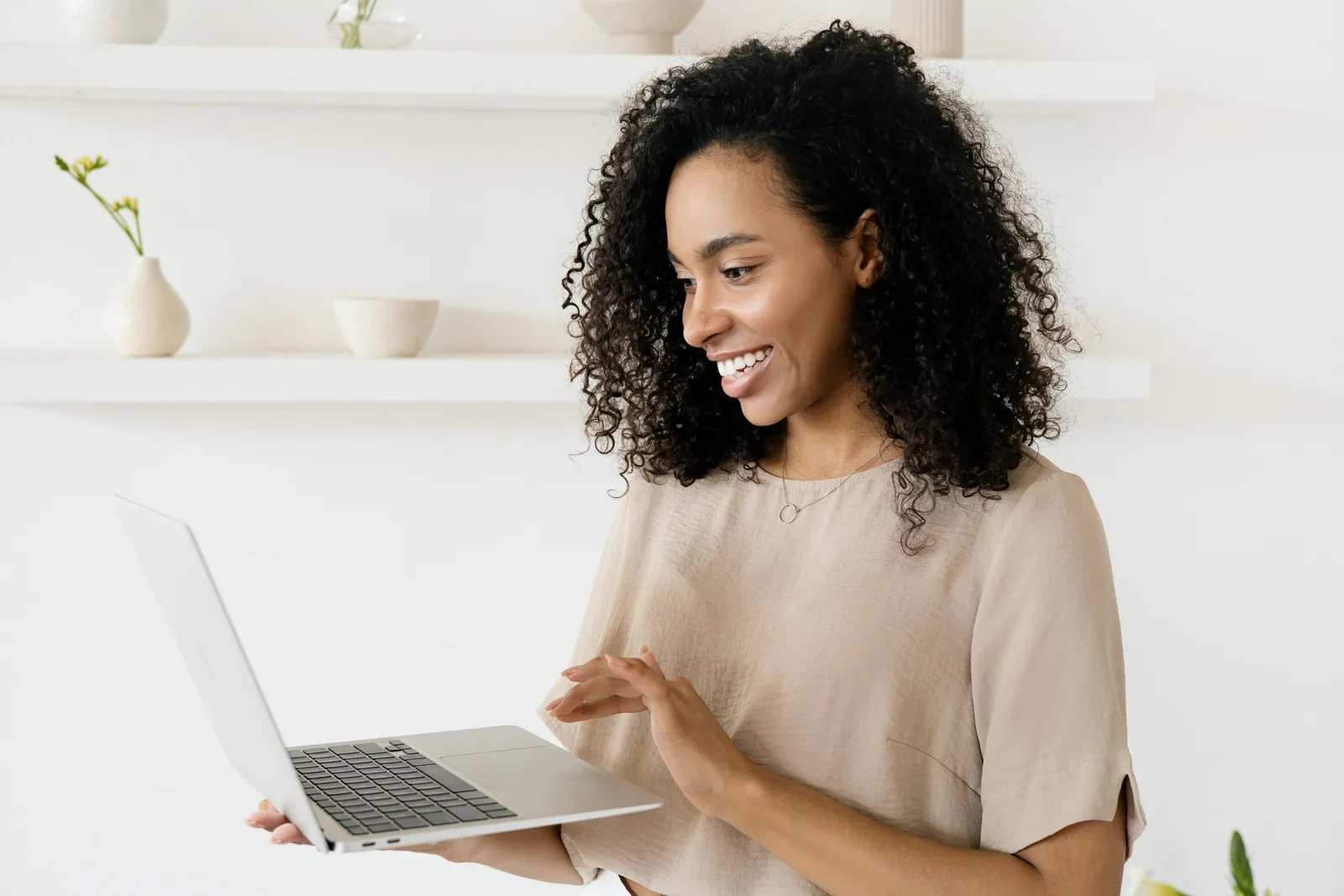 Freelancer smiling while using a laptop in a modern home office.